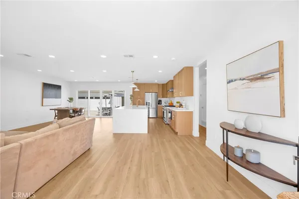 a living room with stainless steel appliances furniture and a kitchen view