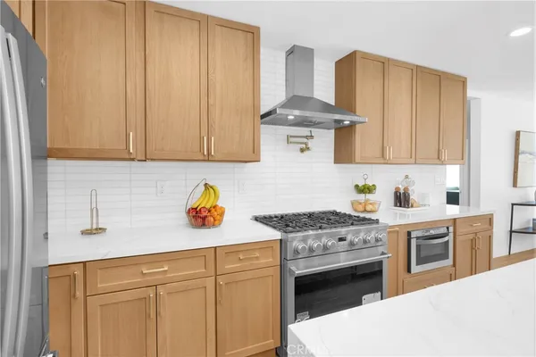 a kitchen with stainless steel appliances granite countertop a stove a sink dishwasher and white cabinets with wooden floor