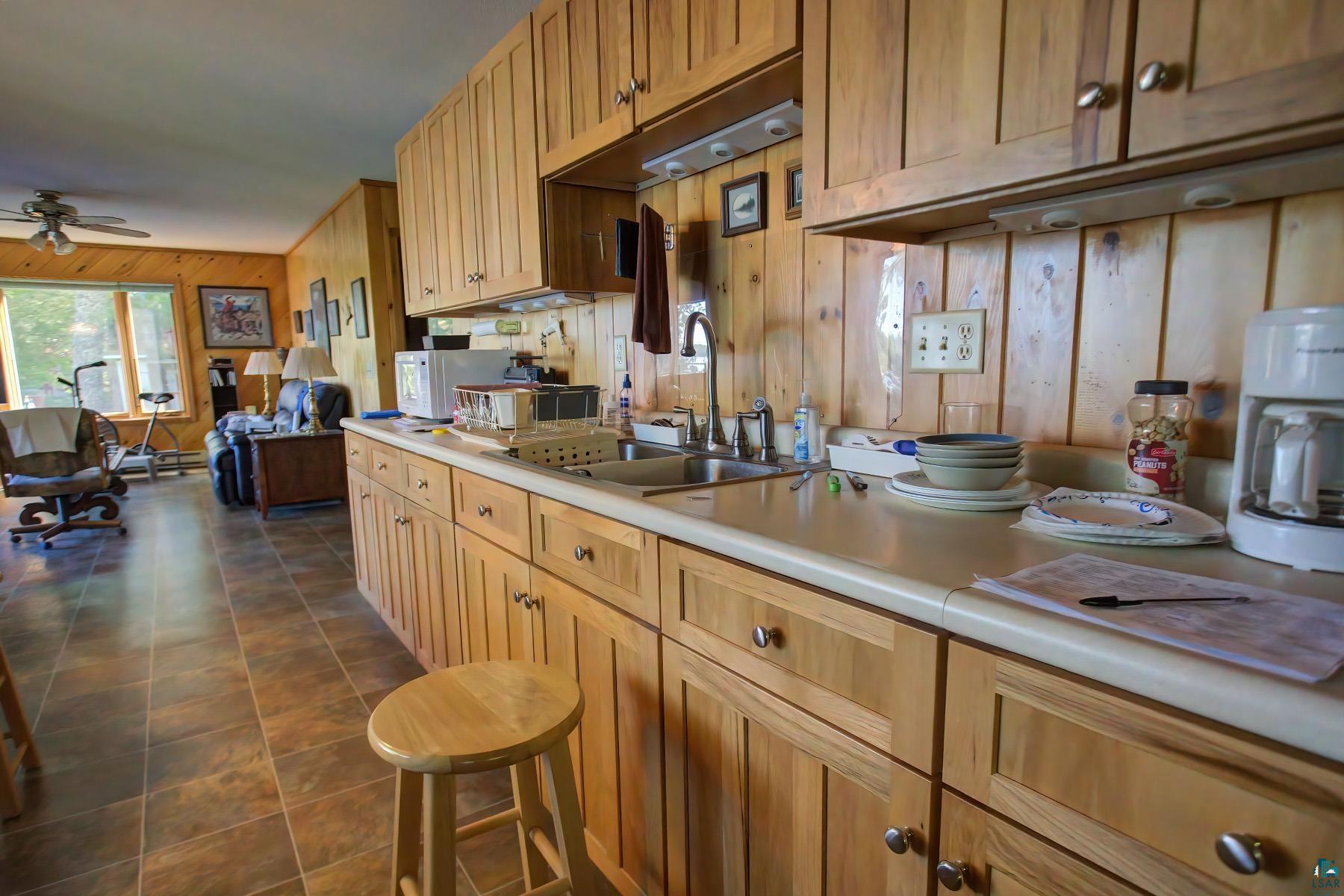 2811 Schaeffer Road Ely, MN 55731 - Photo 24 of 40 Wood-paneled walls and cabinetry, ceiling fan, tile flooring, built-in sink, and expansive windows