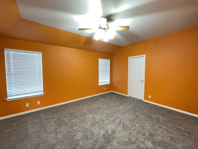 a view of an empty room with chandelier fan and a window