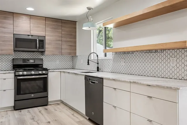 a kitchen with stainless steel appliances granite countertop a sink a stove and a microwave