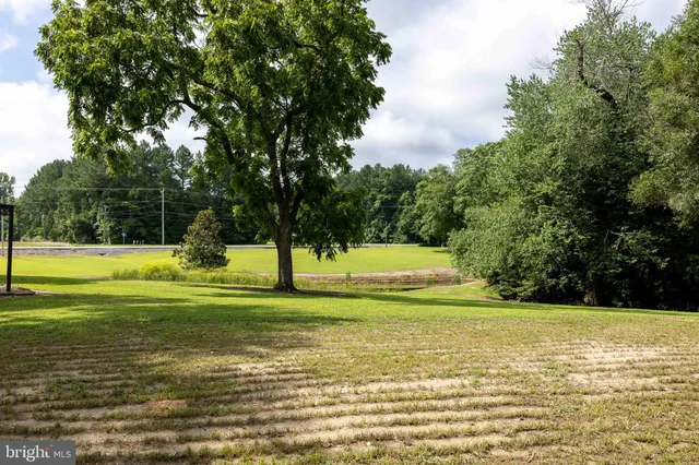 a view of a lake with a yard and trees in the background