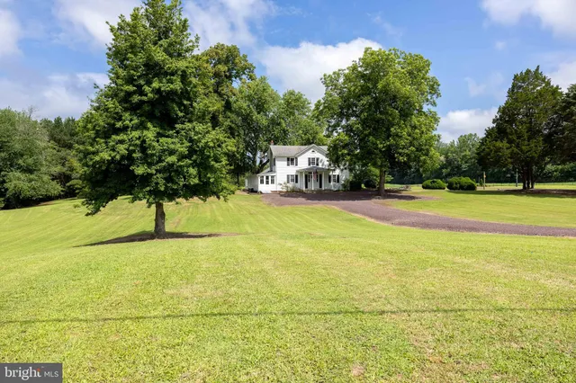 a view of swimming pool with lawn chairs and large trees