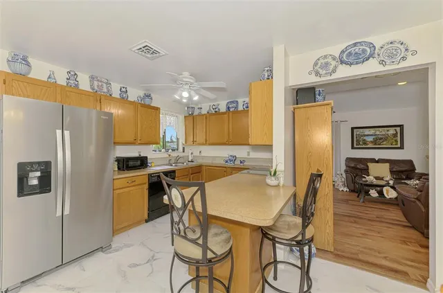 a kitchen with stainless steel appliances a refrigerator a stove a dining table and chairs with wooden floor