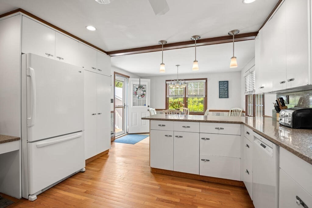 155 Main Street Winchester, MA 01890 - Photo 11 of 35 a large white kitchen with a refrigerator a sink dishwasher a stove and white cabinets with wooden floor