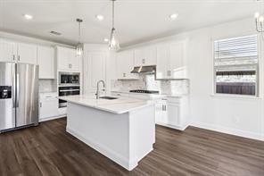 2448 Glacier Ridge Corinth, TX 76210 - Photo 10 of 27 a kitchen with stainless steel appliances granite countertop a refrigerator a stove a sink and white cabinets with wooden floor