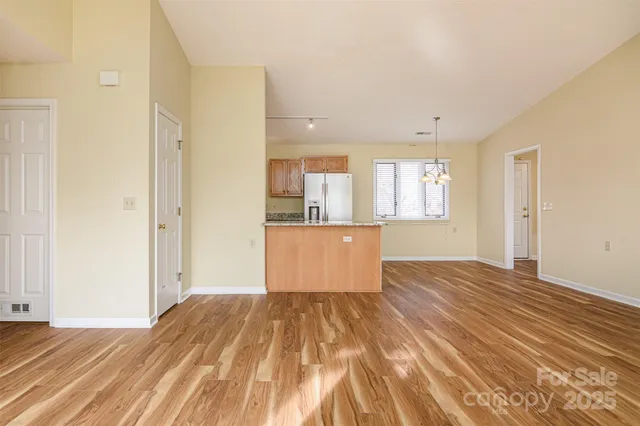 a view of kitchen and empty room with wooden floor