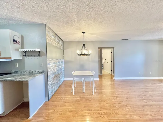 a view of a kitchen with kitchen island granite countertop wooden floor and a refrigerator