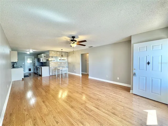 a view of a livingroom with a dinning area hardwood floor and a ceiling fan