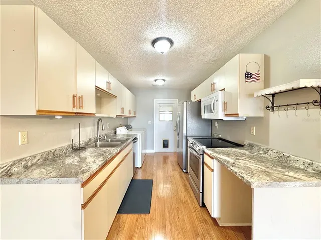 a large kitchen with stainless steel appliances granite countertop a lot of counter space and wooden floor