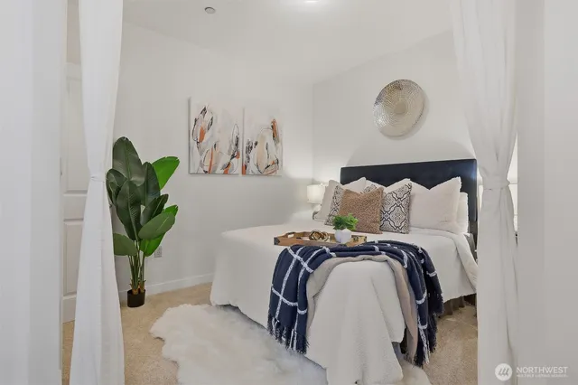 a bed sitting in a bedroom next to a window and a potted plant