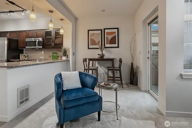 a living room with stainless steel appliances furniture a rug and white walls
