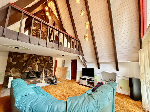 12498 East Wilderness Road Brighton, UT 84121 - Photo 40 of 40 Spacious living area featuring a prominent stone fireplace, a vaulted ceiling with exposed wood beams, and a wood-paneled balcony