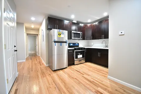 a kitchen with stainless steel appliances kitchen island granite countertop a refrigerator and a sink