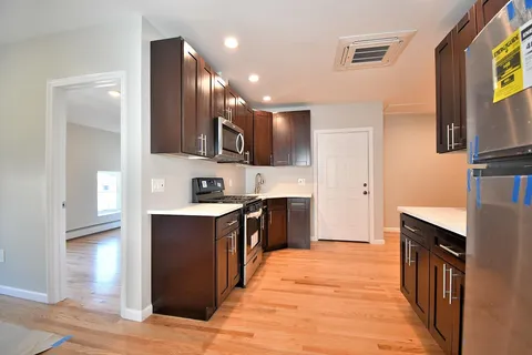a large kitchen with stainless steel appliances kitchen island granite countertop a stove and a sink