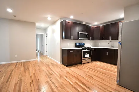 a large kitchen with stainless steel appliances kitchen island a large counter top and wooden floor