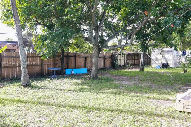 a backyard of a house with large trees and wooden fence