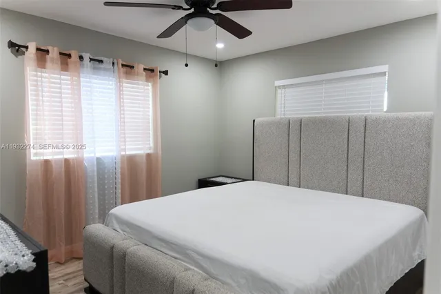 a large bed sitting in a bedroom next to a window and a chandelier