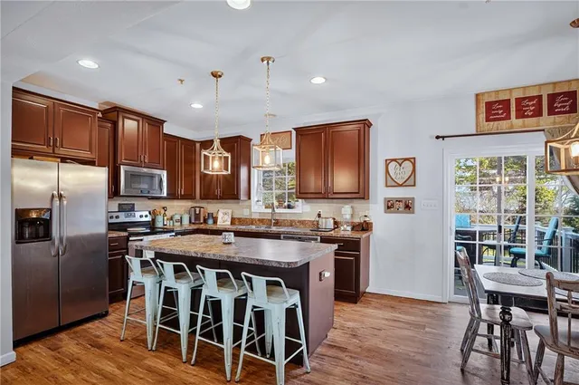a kitchen with stainless steel appliances granite countertop a stove a refrigerator a kitchen island a table and chairs
