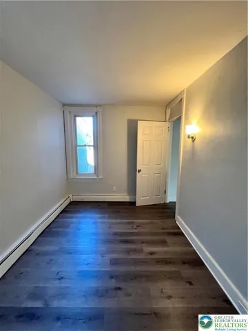 a view of an empty room with wooden floor and window
