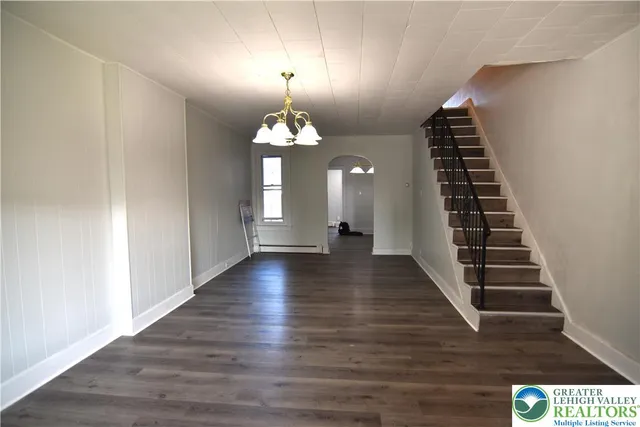 a view of a hallway with wooden floor staircase and a living room