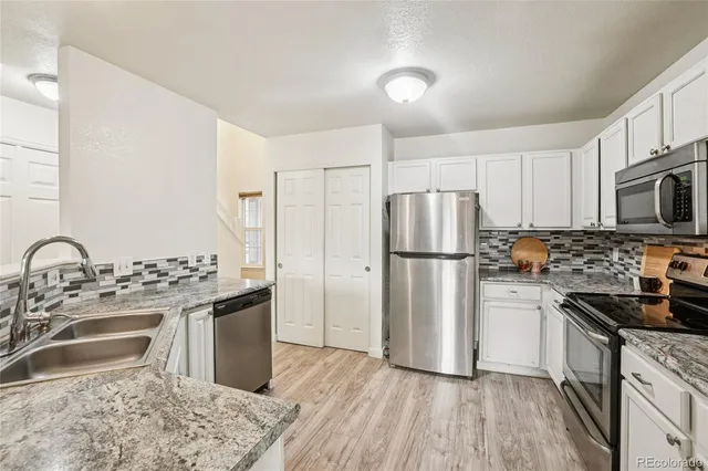 a kitchen with stainless steel appliances granite countertop a refrigerator stove and sink