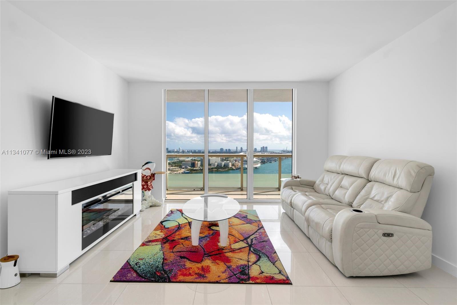 50 Biscayne Boulevard, Unit 3108 Miami, FL 33132 - Photo 5 of 26 a living room with furniture a flat screen tv and a floor to ceiling window