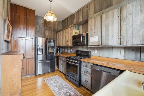 a kitchen with stainless steel appliances granite countertop a refrigerator a stove and a sink with wooden floor