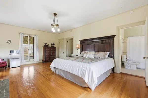 a bedroom with a large bed and wooden floor