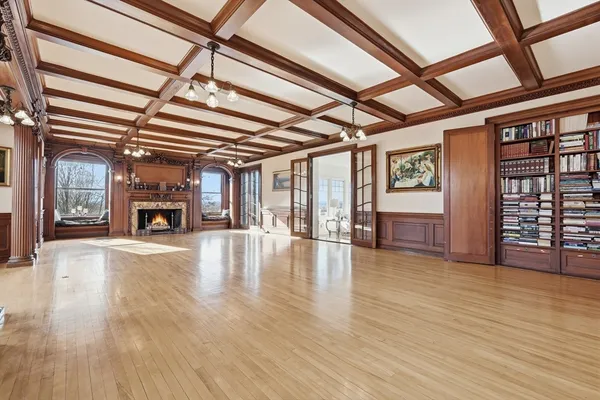 a view of an empty room with wooden floor windows and a fireplace