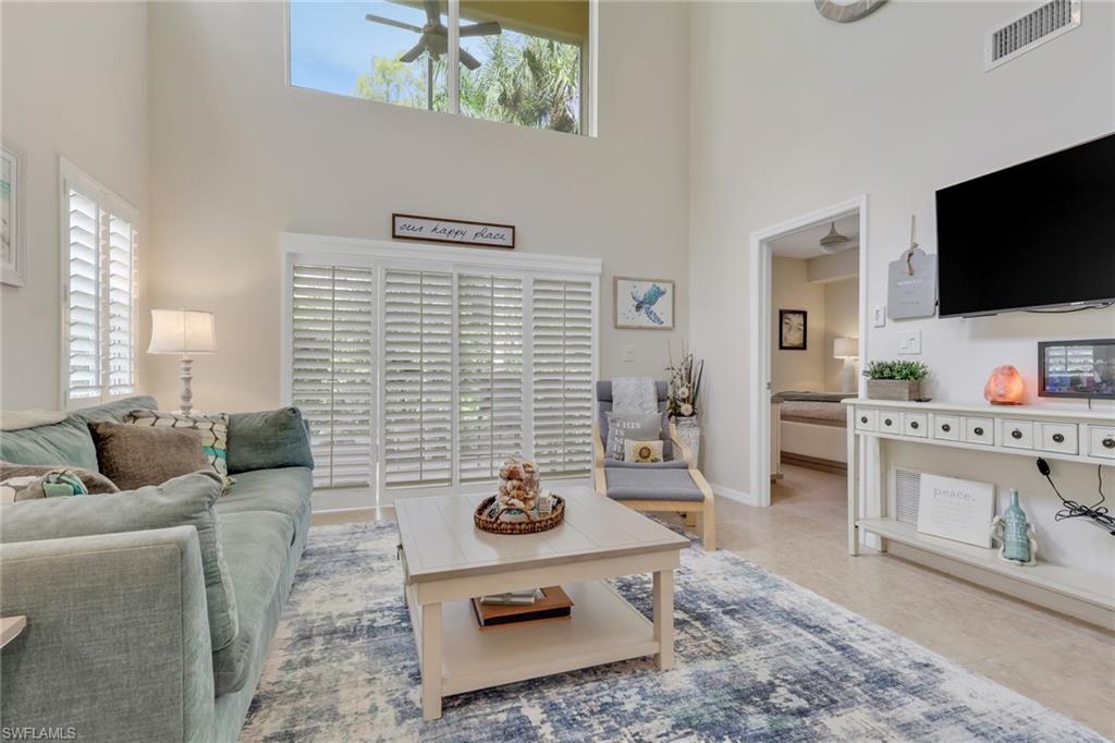 Living area with a towering ceiling, ceiling fan, and tile patterned floors