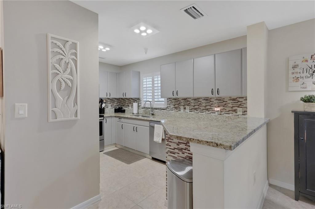 4500 Botanical Pl Circle, Unit 101 Naples, FL 34112 - Photo 12 of 44 a kitchen with stainless steel appliances granite countertop a sink stove and refrigerator