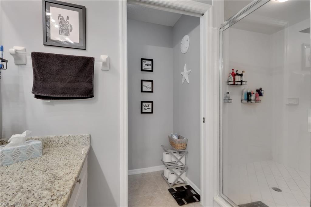 4500 Botanical Pl Circle, Unit 101 Naples, FL 34112 - Photo 19 of 44 a bathroom with a granite countertop sink a toilet and a shower