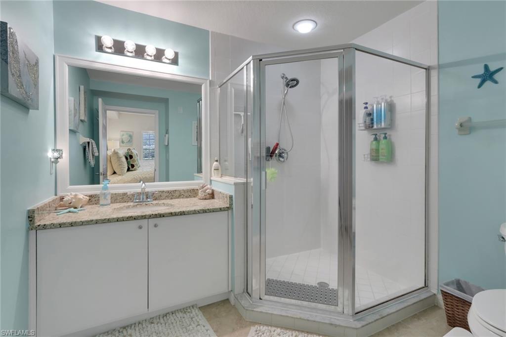 4500 Botanical Pl Circle, Unit 101 Naples, FL 34112 - Photo 25 of 44 a bathroom with a granite countertop shower sink and mirror