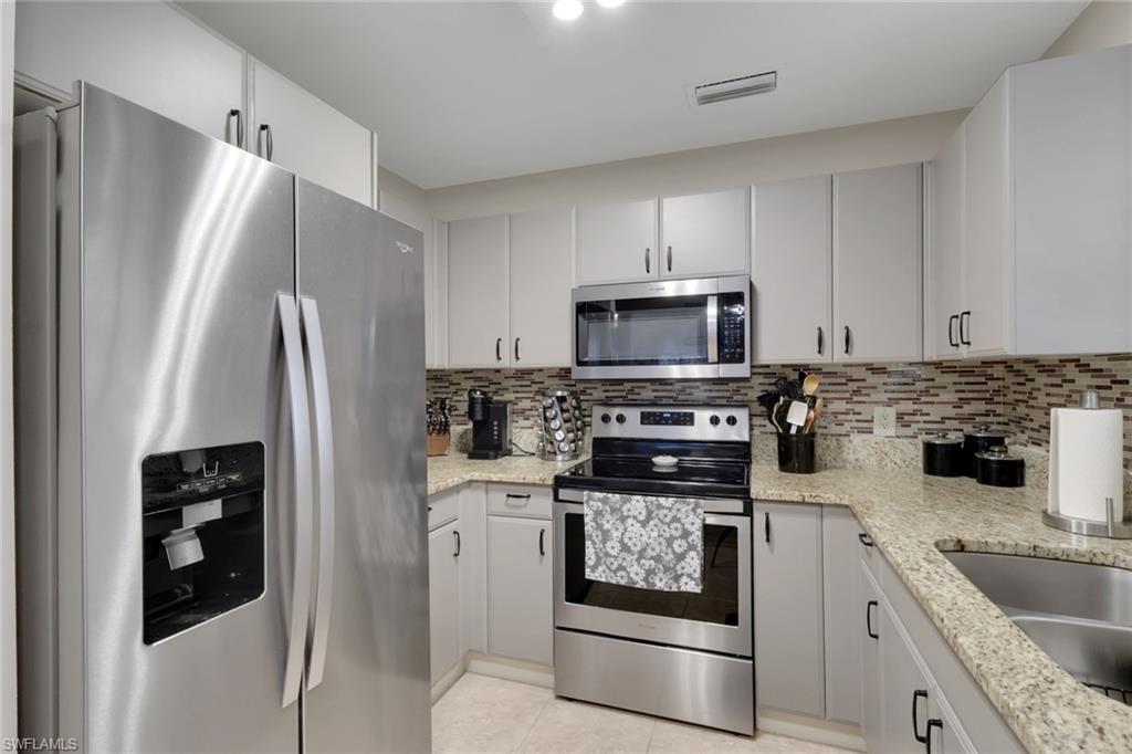 4500 Botanical Pl Circle, Unit 101 Naples, FL 34112 - Photo 9 of 44 a kitchen with stainless steel appliances granite countertop a refrigerator stove and sink