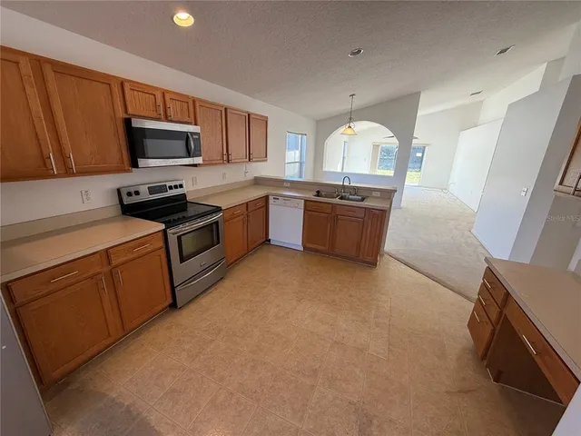 a large kitchen with stainless steel appliances granite countertop a stove a sink dishwasher and a microwave