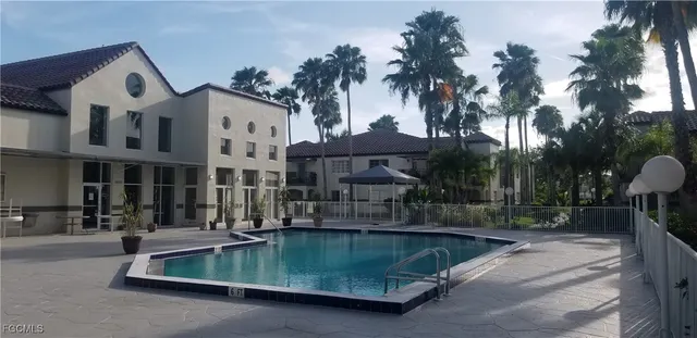 a view of a fountain with a bench in front of house