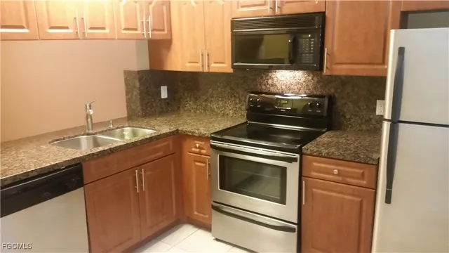 a kitchen with granite countertop cabinets stainless steel appliances and a counter space
