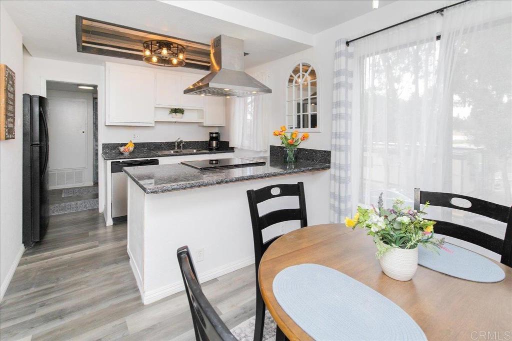 a kitchen with stainless steel appliances kitchen island granite countertop a table chairs in it and wooden floors