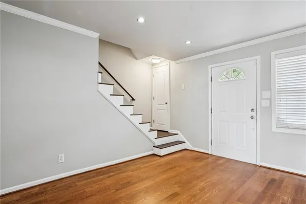 a view of an empty room with wooden floor and stairs