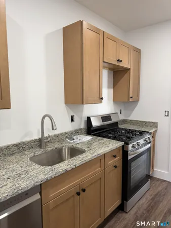 a kitchen with a stove a refrigerator and a sink with wooden floor