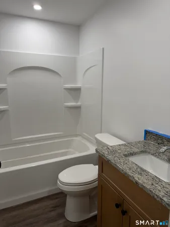 a bathroom with a granite countertop toilet and a bathtub