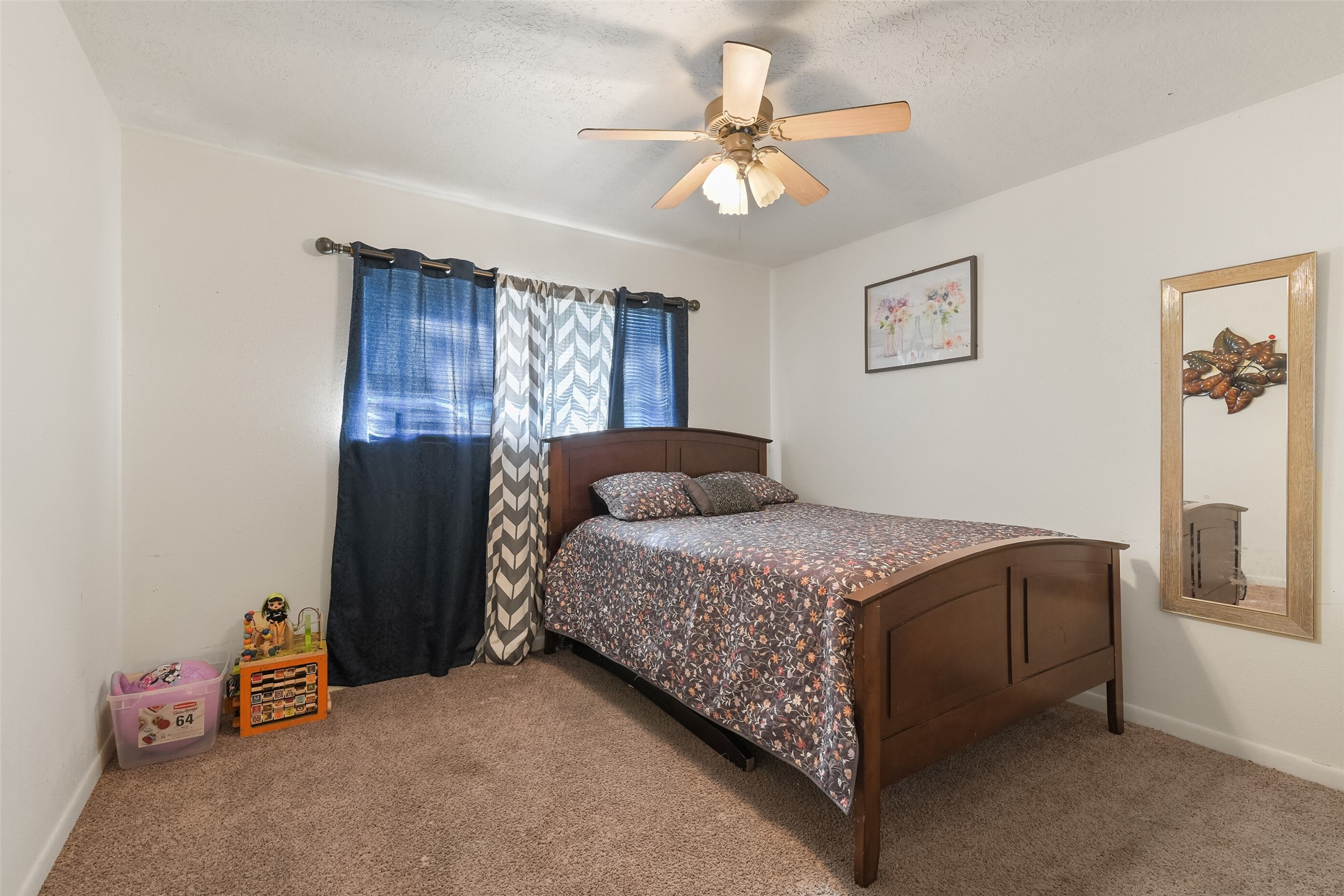 217 Lazy Lane, Unit B Conroe, TX 77301 - Photo 19 of 27 a bedroom with a bed and a chandelier