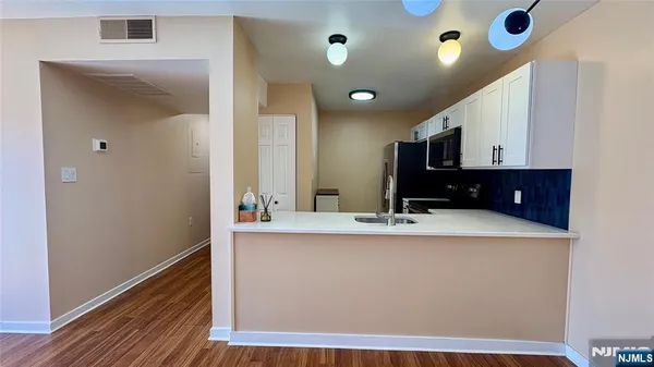 a room with kitchen island a sink and wooden floor