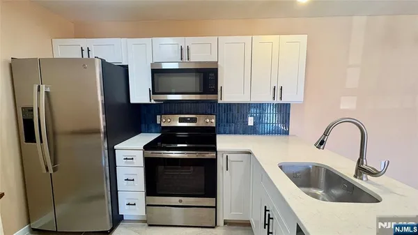a kitchen with stainless steel appliances a refrigerator a sink a stove and cabinets