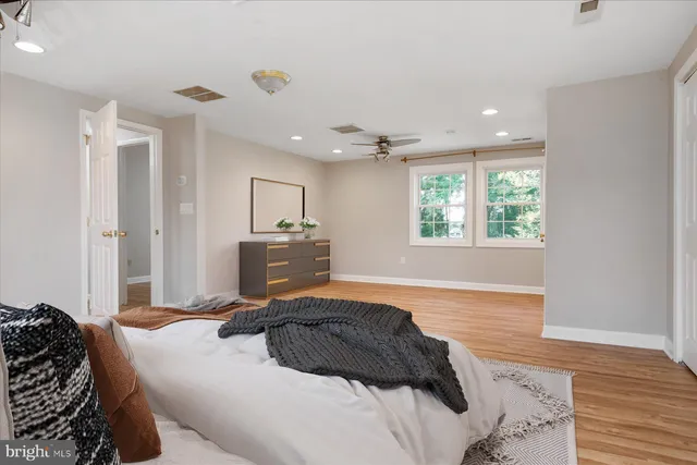 a spacious bedroom with a bed and wooden floor
