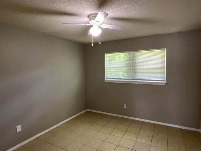 an empty room with windows and fan