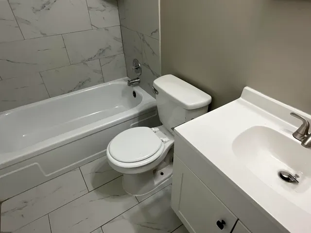 a white toilet sitting next to a bath tub