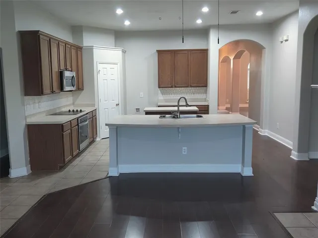 a kitchen with kitchen island granite countertop a sink and a stove top oven
