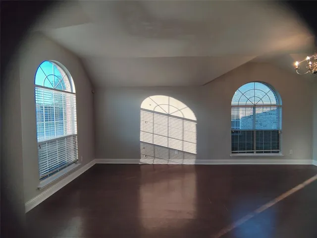 an empty room with wooden floor windows and glass door